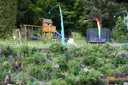 Blühender Hanggarten mit Trampolin im Hintergrund